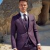 Moderner Hochzeitsanzug in Lila mit Weste, schmalem Revers und Krawatte, getragen vor Felskulisse im Freien