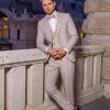 Eleganter, beigefarbener Bräutigamanzug mit Weste und Fliege – stilvoller Hochzeitslook für den modernen Gentleman in romantischer Abendkulisse.