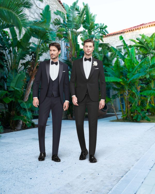 Klassischer Smoking in Schwarz und Dunkelblau für den Bräutigam – stilvoller Hochzeitslook mit Fliege in eleganter mediterraner Kulisse.