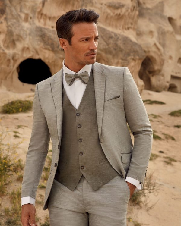 Grauer Bräutigamanzug mit Weste und Fliege – stilvoller Hochzeitslook für moderne Bräutigame in natürlicher Kulisse.