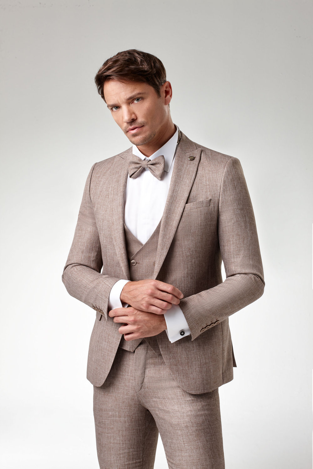 Bräutigamanzug in elegantem Camel-Ton mit Weste und Fliege – moderner Hochzeitslook für stilbewusste Herren.