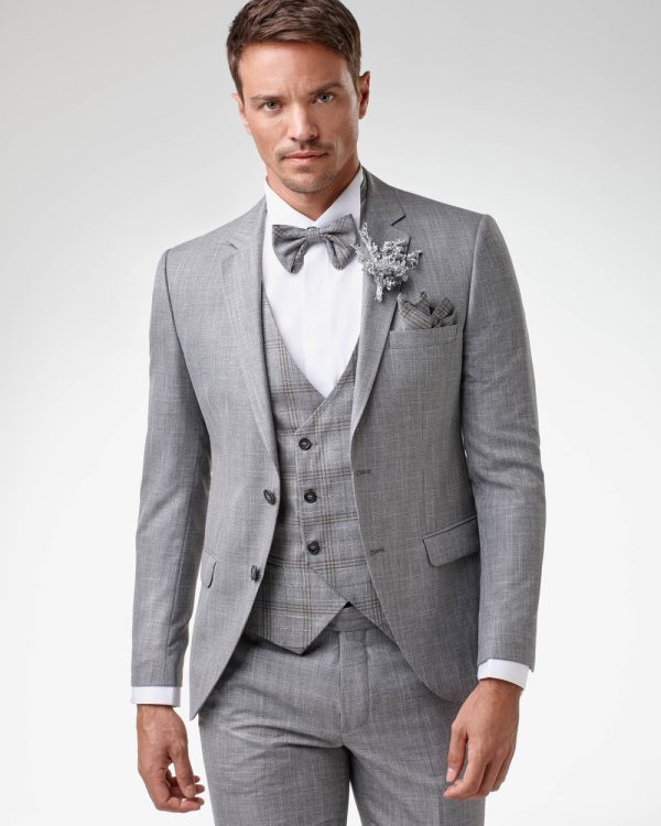 Grauer Bräutigamanzug mit Weste, Fliege und Ansteckblume – eleganter Hochzeitslook für stilbewusste Herren.