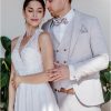Moderner Hochzeitsanzug in Beige mit Weste und gemusterter Fliege – edler Bräutigam-Look gemeinsam mit Braut im weißen Kleid.