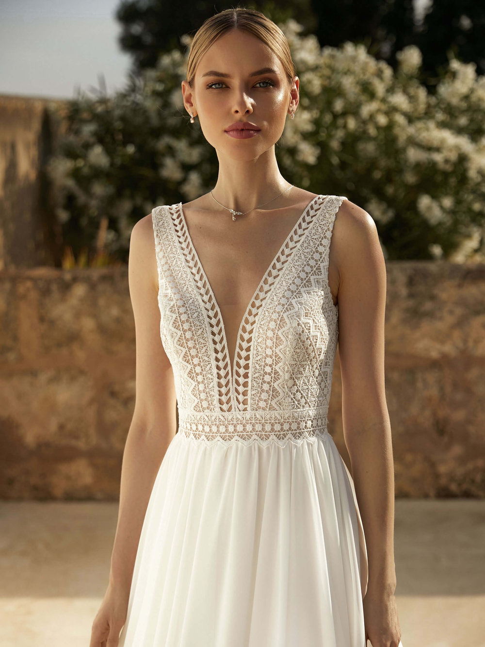 Detaillierte Nahaufnahme eines Boho & Vintage Brautkleids mit tiefem V-Ausschnitt und floraler Häkelspitze