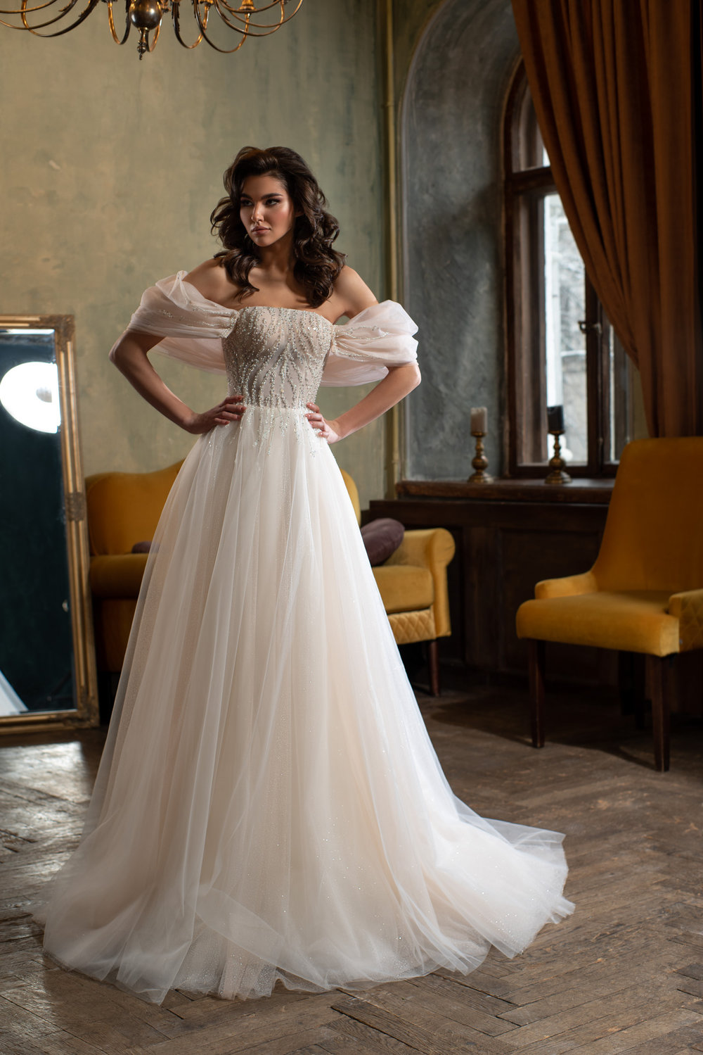 Romantische Frontansicht eines Prinzessin-Brautkleides mit schulterfreien Puffärmeln, glitzerndem Oberteil und weitem Tüllrock.