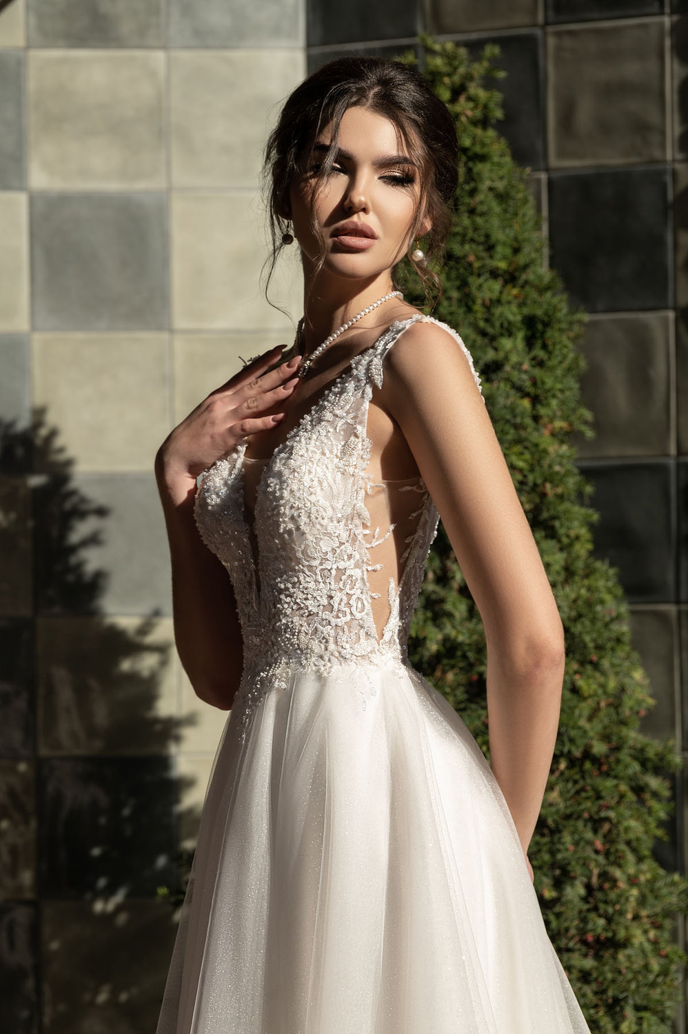 A-Linie Brautkleid mit transparentem Tüll, tiefem V-Ausschnitt und floraler Tattoo-Spitze, Nahaufnahme von vorne bei Tageslicht, zarte Träger und elegante Silhouette.