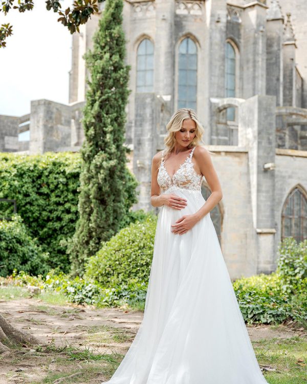 Umstandsbrautkleid mit floraler Spitze und weitem Rock vor historischer Kulisse