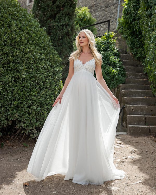 Umstandsbrautkleid mit zartem Spitzenoberteil und fließendem Rock in romantischer Gartenkulisse