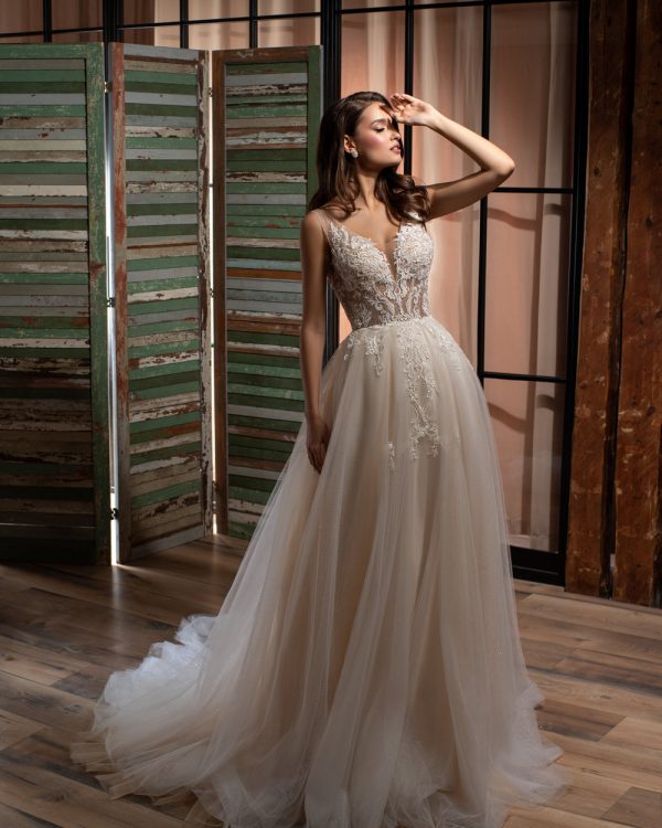 Prinzessin Brautkleid mit tiefem V-Ausschnitt und floral besticktem Spitzenoberteil, Tüllrock in fließender A-Linie, fotografiert vor rustikalem Holzdekor.