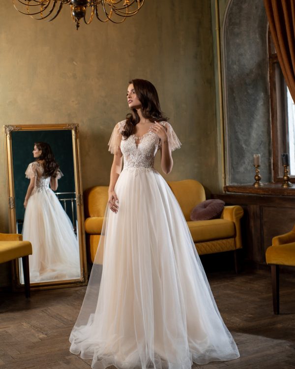 Romantisches Prinzessin Brautkleid mit zartem Tüllrock und aufwendig besticktem Oberteil, fotografiert in einem Vintage-Raum mit Spiegel und Kronleuchter.