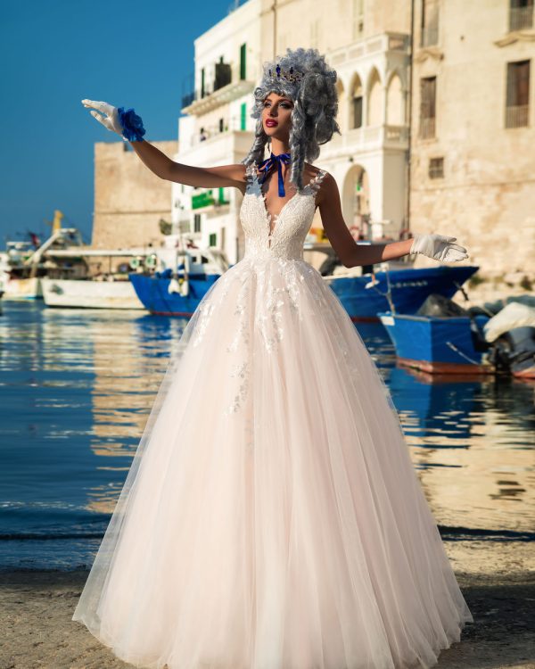 Prinzessin Brautkleid mit Tüllrock, tiefem Rückenausschnitt und Spitzenoberteil – Braut posiert an malerischem Hafen mit maritimer Kulisse.