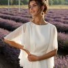Nahaufnahme eines Chiffon-Brautkleides mit fließendem Schnitt und lockeren Flügelärmeln, fotografiert im Lavendelfeld.