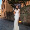 Fit & Flare Brautkleid mit Spitze, Reißverschluss und tiefem Rückenausschnitt – elegante Braut posiert auf mediterraner Straße mit sommerlichen Accessoires.