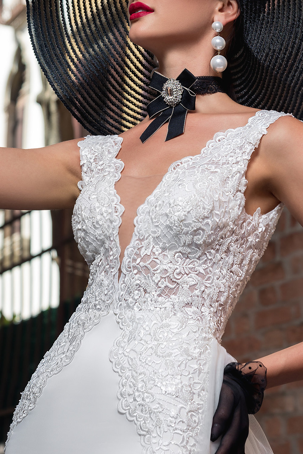 Schmales Fit & Flare Hochzeitskleid mit tiefem V-Ausschnitt, filigraner Spitze und figurbetontem Schnitt – moderner Glamour-Look für urbane Braut.