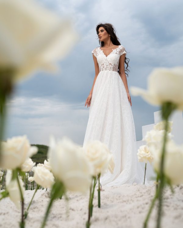 A-Linie Brautkleid mit Spitzenrock, kurzen Ärmeln und langer Knopfleiste, vorne fotografiert unter blauem Himmel