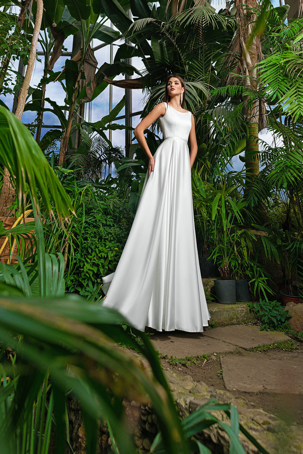 A-Linien Brautkleid aus Satin mit tiefem Rückenausschnitt, elegante Silhouette, fotografiert im Gewächshaus.