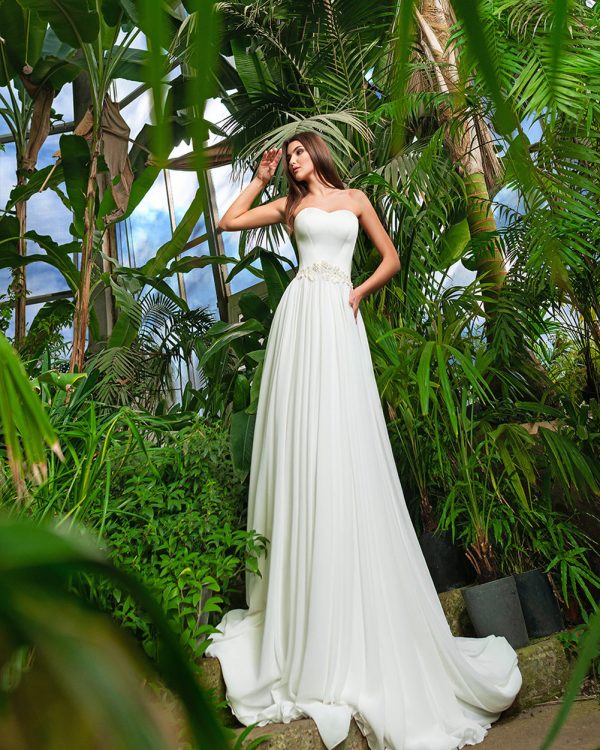 A-Linie Brautkleid mit fließendem Rock und Herzausschnitt, fotografiert in tropischer Gartenkulisse.