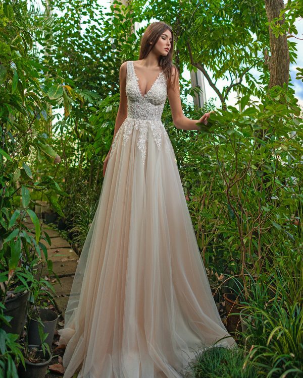 A-Linie Brautkleid mit tiefem V-Ausschnitt, Spitzenoberteil und fließendem Tüllrock, aufgenommen im Gewächshaus.