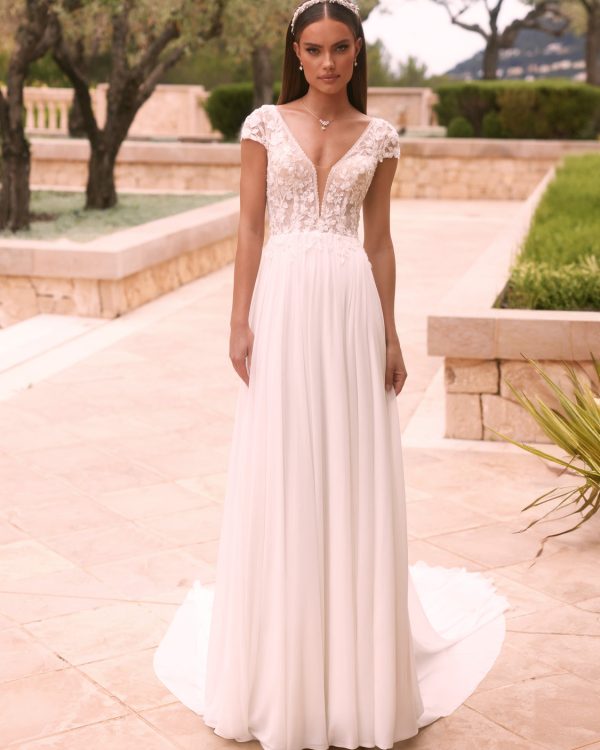 Romantisches Brautkleid mit floraler Spitze, tiefem V-Ausschnitt, kurzen Ärmeln und fließendem Rock, aufgenommen im Gartenbereich