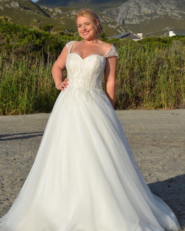 Prinzessinnen Brautkleid mit Herzausschnitt, transparenten Trägern und ausgestelltem Rock, getragen von einer Curvy Braut in der Natur