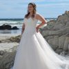 Plus Size Brautkleid mit herzförmigem Ausschnitt, floraler Spitze und Tüllrock, fotografiert am Strand vor Felsen und Meer