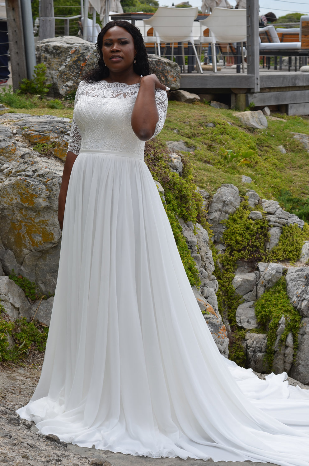 Detailansicht des Oberteils mit halbtransparenten 3/4-Spitzenärmeln, floralen Applikationen und rundem Ausschnitt – figurschmeichelnd und edel.