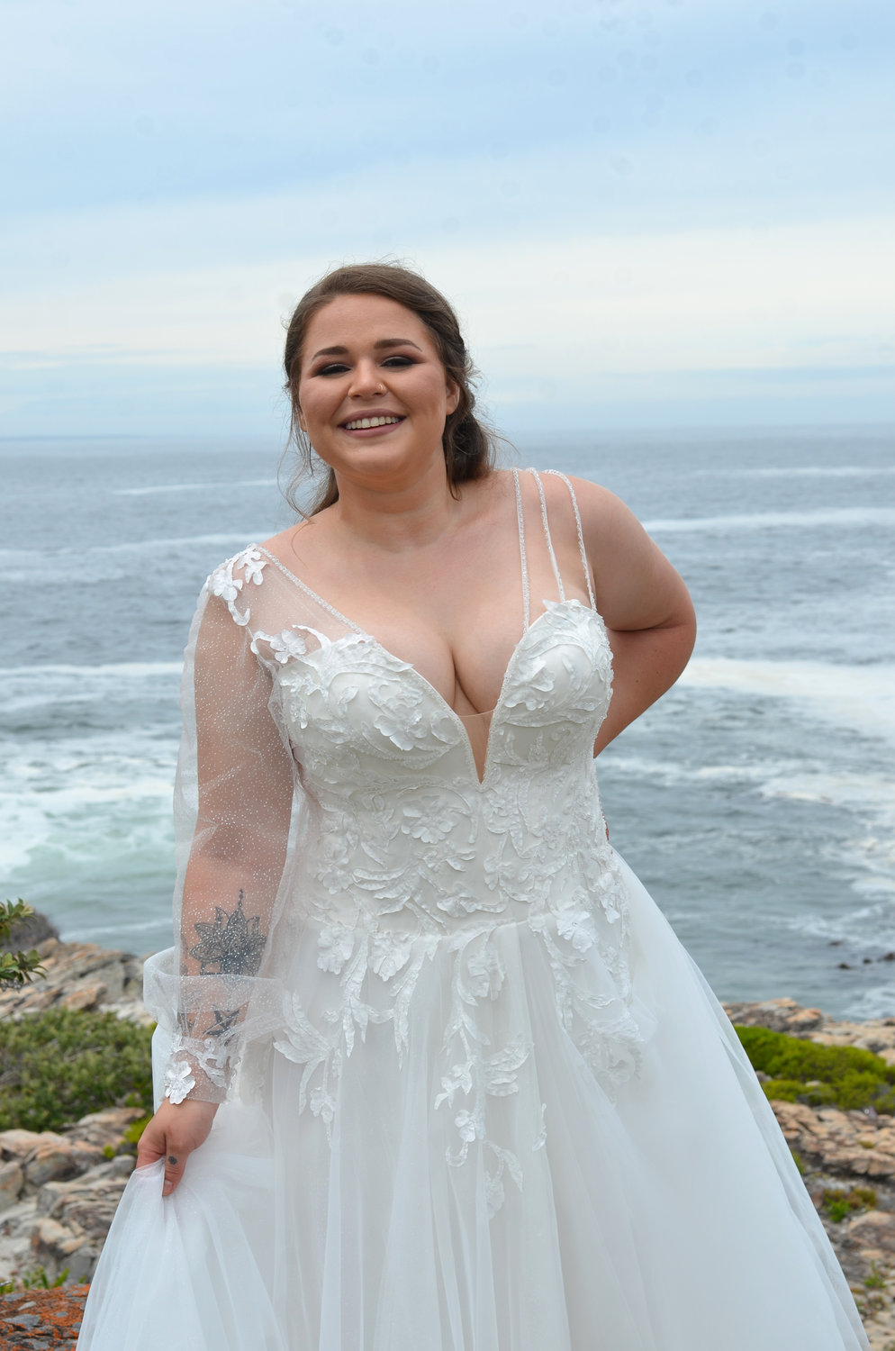 Detailaufnahme des Mieders mit tiefem V-Ausschnitt, floralen Glitzerapplikationen, transparenten Ärmeln und zarten Trägern.