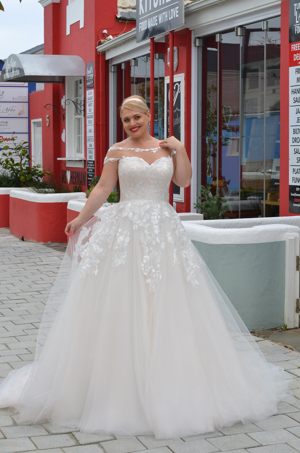 Frontansicht des Brautkleides mit Herzausschnitt unter transparentem Tüll, floralen Spitzenapplikationen und fließendem Tüllrock.